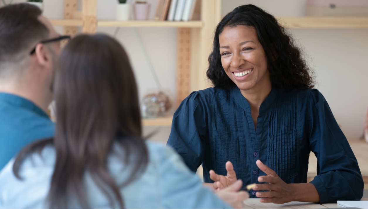A real estate agent smiling while speaking to clients